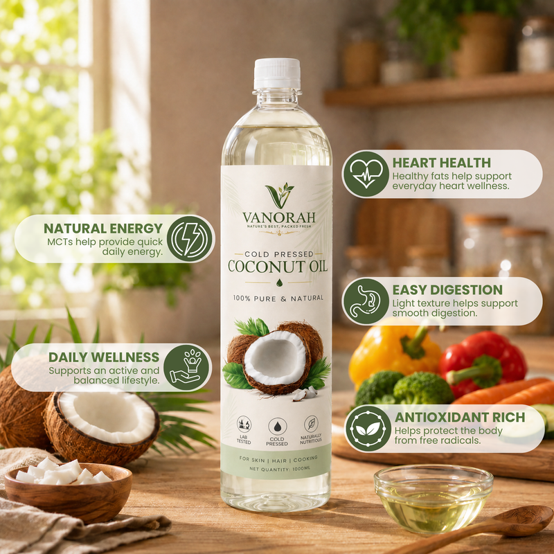 A bottle of VANORAH Cold Pressed Coconut Oil stands on a wooden table in a warm kitchen setting, surrounded by fresh coconuts, a small bowl of oil, and colorful fruits and vegetables. Text callouts on both sides highlight benefits like natural energy, heart health, digestion, and antioxidant richness.